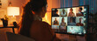 © Ai Studio - In an evening home office lit by warm lights, a woman is engaged in a video conference, communicating with multiple colleagues displayed on her large screen.