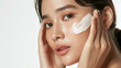 © whoopwhoops - pretty beautiful indonesian or asian model woman face applies light white cream on her face, beauty skincaere studio promo, white background