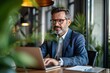 © Yuliia - young businessman video conferencing with a colleague on a laptop at his office desk.