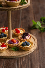 Wall Mural - Berry tartlets with butter cream lie on a wooden whatnot outdoors on the table