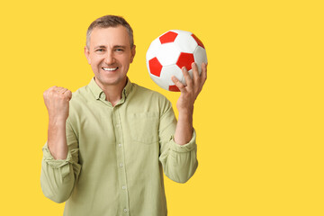 Poster - Happy handsome mature man with soccer ball on yellow background