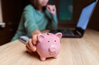 © Zhanna - The girl puts her savings in a piggy bank.