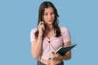 © Pixel-Shot - Pretty young woman with notebook trying to remember something on blue background