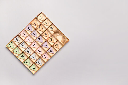 Alphabet in wooden box on grey background. Top view