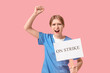 © Pixel-Shot - Protesting female doctor holding placard with text ON STRIKE against pink background