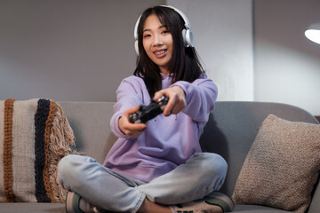 Sticker - Young beautiful Asian woman with game pad on cozy sofa in living room