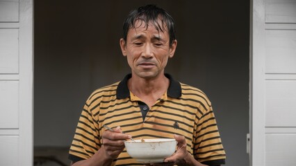 Canvas Print - A man holding a bowl of food and eating it, AI