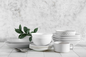 Wall Mural - Stylish tableware with leaves on tile table near grunge wall