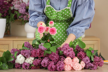 Wall Mural - Female florist making beautiful bouquet with lilacs and roses in flower shop