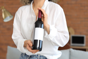 Woman with bottle of wine at home, closeup