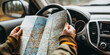 © Andres Mejia - Tourist holding paper map navigating while driving car