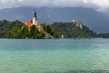 Wall Mural - Panoramic view from Lake Bled, beauty heritage in Slovenia. Island with church and castle in the background create a dream setting. View from Ojstrica and Mala Osojnica with the heart-shaped bench.