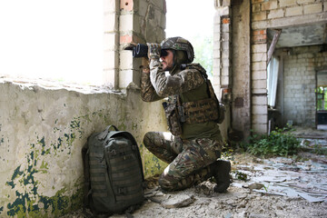 Wall Mural - Military mission. Soldier in uniform with binoculars inside abandoned building