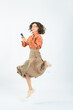 © metamorworks - Full body photo of a Caucasian woman jumping while using a smartphone
