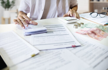 Wall Mural - Asian man with many document on desk checking passbook calculate cost of starting a business and apply for loan approval.