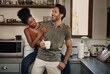 © peopleimages.com - Interracial couple, together and happiness with tea in kitchen for wellness, morning routine or bonding in home. Man, woman and smile in house with coffee for health, relax with partner or care