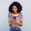 © peopleimages.com - Studio, chat and African woman with smartphone for scroll, excited and online connection with contact. Female person, social media and cellphone with mobile app, gossip and message by gray background