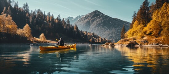 Photo of person paddling boat in the calm of river near an autumn forest with the mountain view.