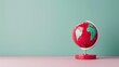 © MAY - A minimalist composition featuring a vibrant red globe set against a plain backdrop, with plenty of copy space for customization. The image is ideal for conveying ideas of global communication and