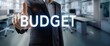 © Stocks Buddy - A businessman in suit pointing at virtual word budget illustrating financial budget concept