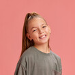 © master1305 - Portrait of attracting young girl, 9 years old child posing with smile, in casual t-shirt and ponytail against peach background. Concept of childhood, human emotions, casual fashion