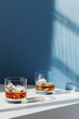 © Bundi - Whisky vases with ice atop a blue background