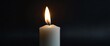 © sevenSkies - a white candle on plain black background for banner with copy space