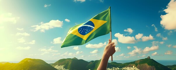 Wall Mural - Hand holding Brazil national flag on blue sky. Happy Independence Day, Labor Day, Proclamation of the Republic. Background with copy space for greeting card, banner, poster