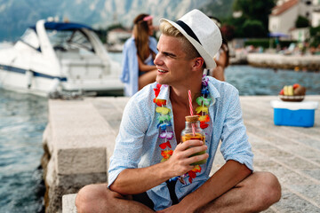 Wall Mural - Happy young man enjoying a tropical cocktail on beach. Travel and summer vacation concept.