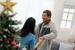 © itchaznong - Elderly Couple Dancing Joyfully Near Christmas Tree in Cozy Living Room with Natural Light
