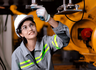 Wall Mural - Industrial engineer working on robot maintenance in AI futuristic electronic technology factory. Female technician checking automated robotic machine. Modern smart woman empowerment in industry 4.0.