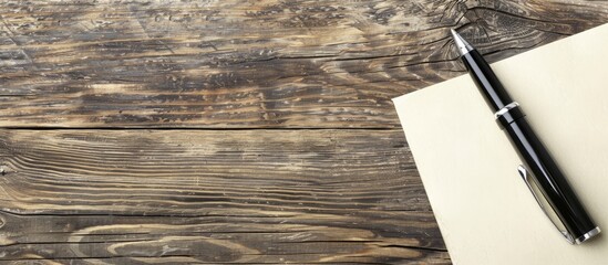 Fototapete - Office wooden table with a pen placed on a blank notepad offering a copy space image
