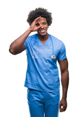 Wall Mural - Afro american surgeon doctor man over isolated background doing ok gesture with hand smiling, eye looking through fingers with happy face.