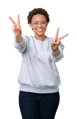 Wall Mural - Young beautiful african american woman wearing glasses over isolated background smiling looking to the camera showing fingers doing victory sign. Number two.