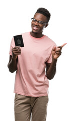 Canvas Print - Young african american man holding canadian passport very happy pointing with hand and finger to the side