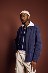 Wall Mural - Handsome African American man standing confidently in front of a brown wall.