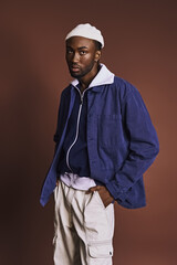 Wall Mural - Handsome young African American man in a blue jacket and white hat.