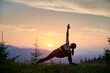 © anatoliy_gleb - Woman practicing yoga outdoors in the mountains in a serene, natural setting. Female performing yoga pose, with backdrop of beautiful mountain landscape at sunrise or sunset.