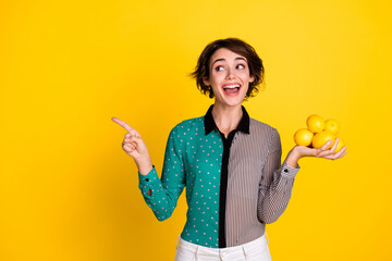 Wall Mural - Photo of charming lovely glad woman wear stylish clothes hold lemon look empty space isolated on yellow color background