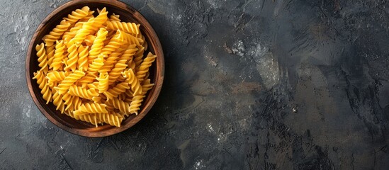 Poster - Top view of uncooked Creste di Gallo pasta presented in a wooden bowl on a dark vintage backdrop with room for text or other graphics in the image. with copy space image