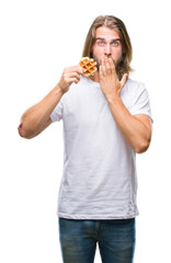 Poster - Young handsome man with long hair over isolated background eating waffle cover mouth with hand shocked with shame for mistake, expression of fear, scared in silence, secret concept