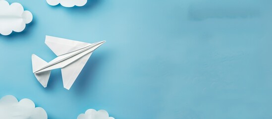 Poster - Top view of white paper origami airplane on pastel blue background with clouds suitable for copy space image