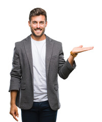 Canvas Print - Young handsome business man over isolated background smiling cheerful presenting and pointing with palm of hand looking at the camera.