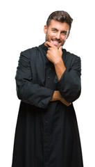 Canvas Print - Young catholic christian priest man over isolated background looking confident at the camera with smile with crossed arms and hand raised on chin. Thinking positive.