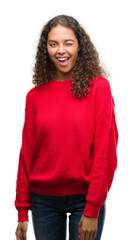 Wall Mural - Young hispanic woman wearing red sweater winking looking at the camera with sexy expression, cheerful and happy face.