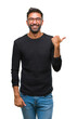 © Krakenimages.com - Adult hispanic man wearing glasses over isolated background smiling with happy face looking and pointing to the side with thumb up.