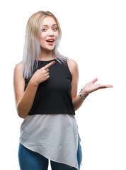 Sticker - Young blonde woman over isolated background amazed and smiling to the camera while presenting with hand and pointing with finger.