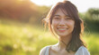 © Nittaya - Happy Asian woman smiling at the camera on green field background.