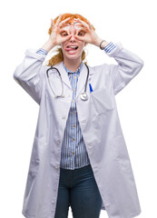 Wall Mural - Young redhead woman wearing doctor uniform doing ok gesture like binoculars sticking tongue out, eyes looking through fingers. Crazy expression.