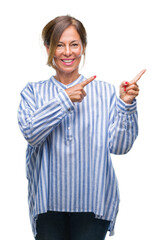 Sticker - Middle age senior hispanic woman over isolated background smiling and looking at the camera pointing with two hands and fingers to the side.